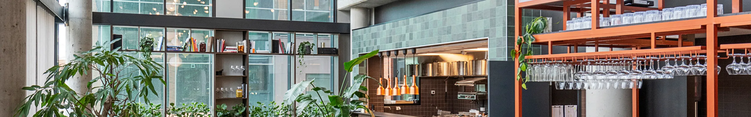 Modern office breakout area interior with high ceilings, black acoustic panels, hanging pendant lights, round tables with burgundy seating, and a bar area with wooden stools and green tiles