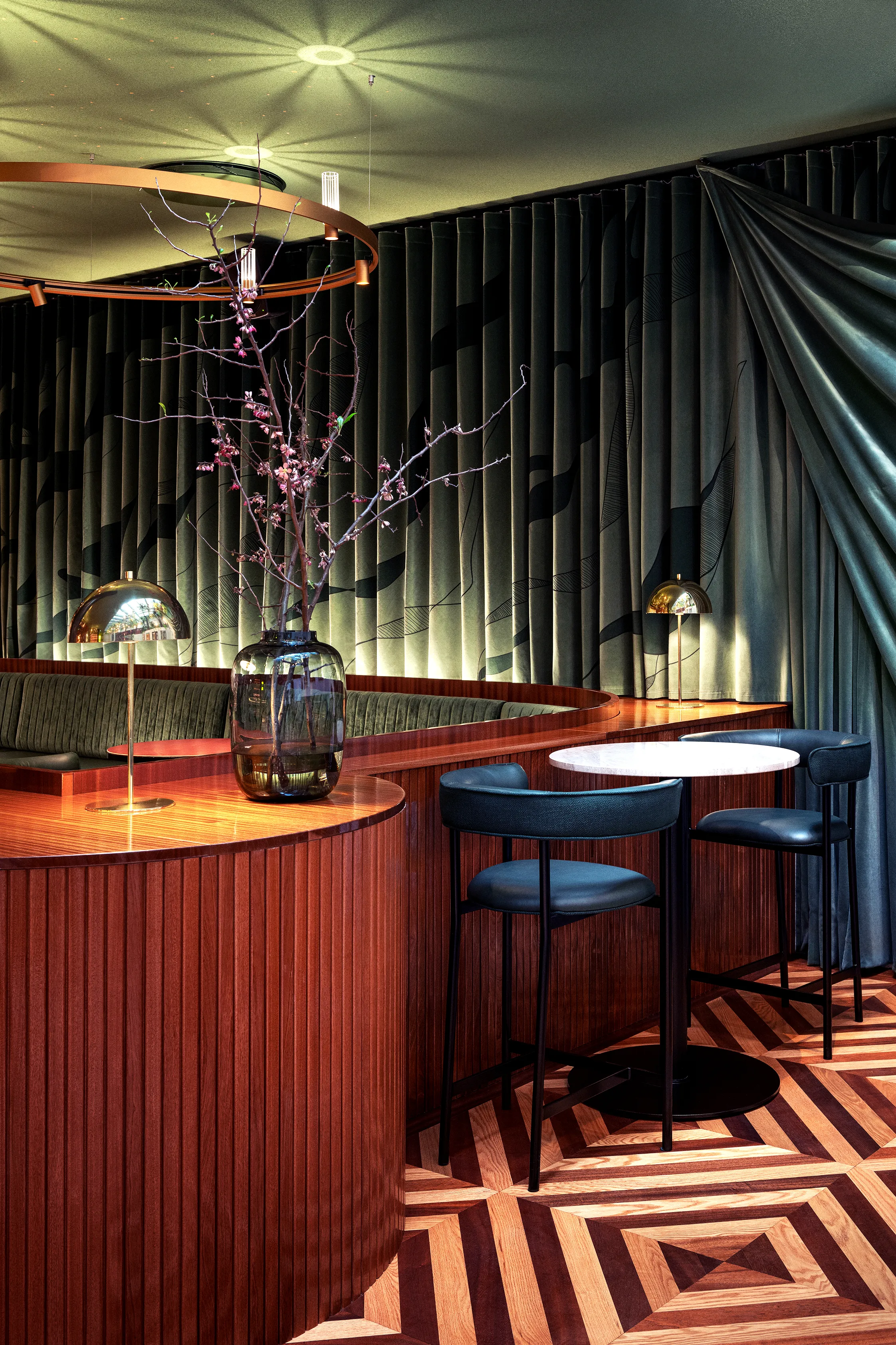 Curved staircase and timber balcony inside Restaurant Brasserie Astoria in Stockholm, featuring a seamless Rockfon Mono Acoustic ceiling and circular lighting above the stairwell.