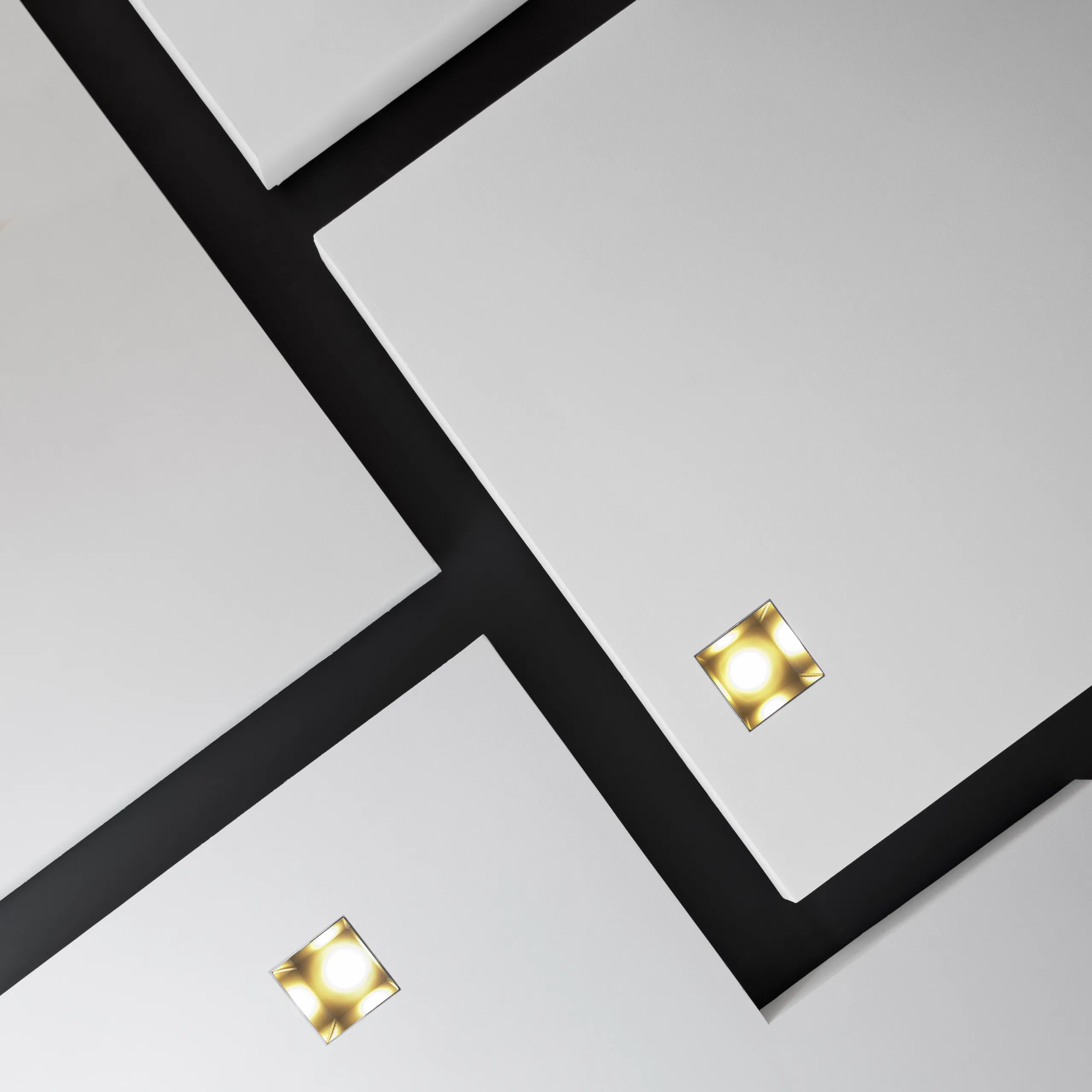 Close-up view of white acoustic ceiling panels installed against a dark background, with integrated square recessed lights