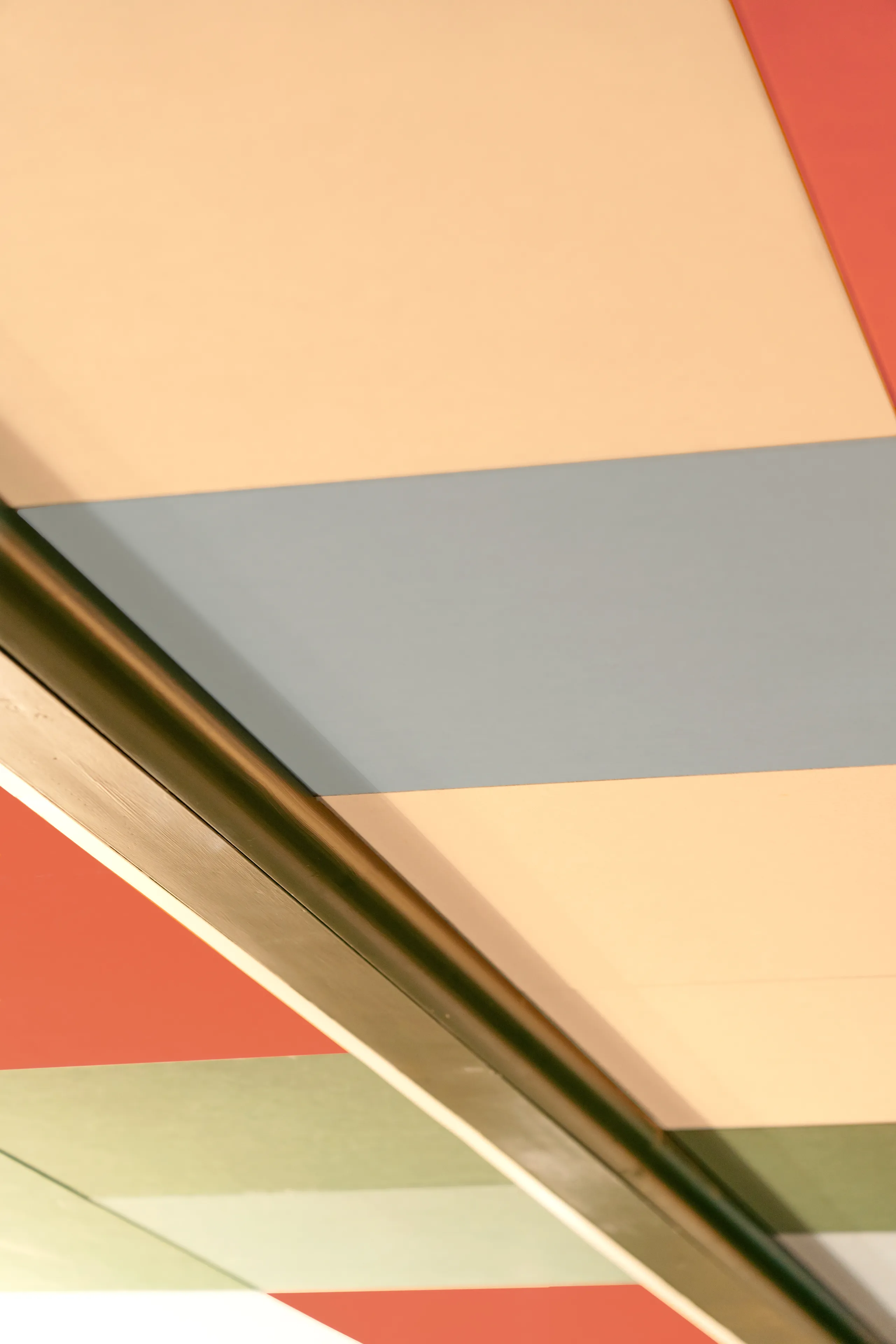 Colorful ceiling with large horizontal stripes in red, blue, green, and beige tones, intersected by a dark, diagonal beam.