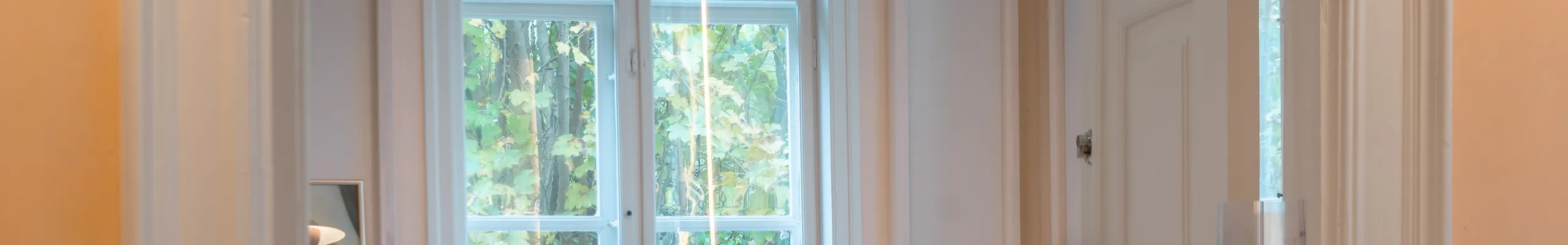 A soft, light-filled playroom where circular acoustic ceiling islands and warm pendant lights create a calm setting as children play beneath large windows