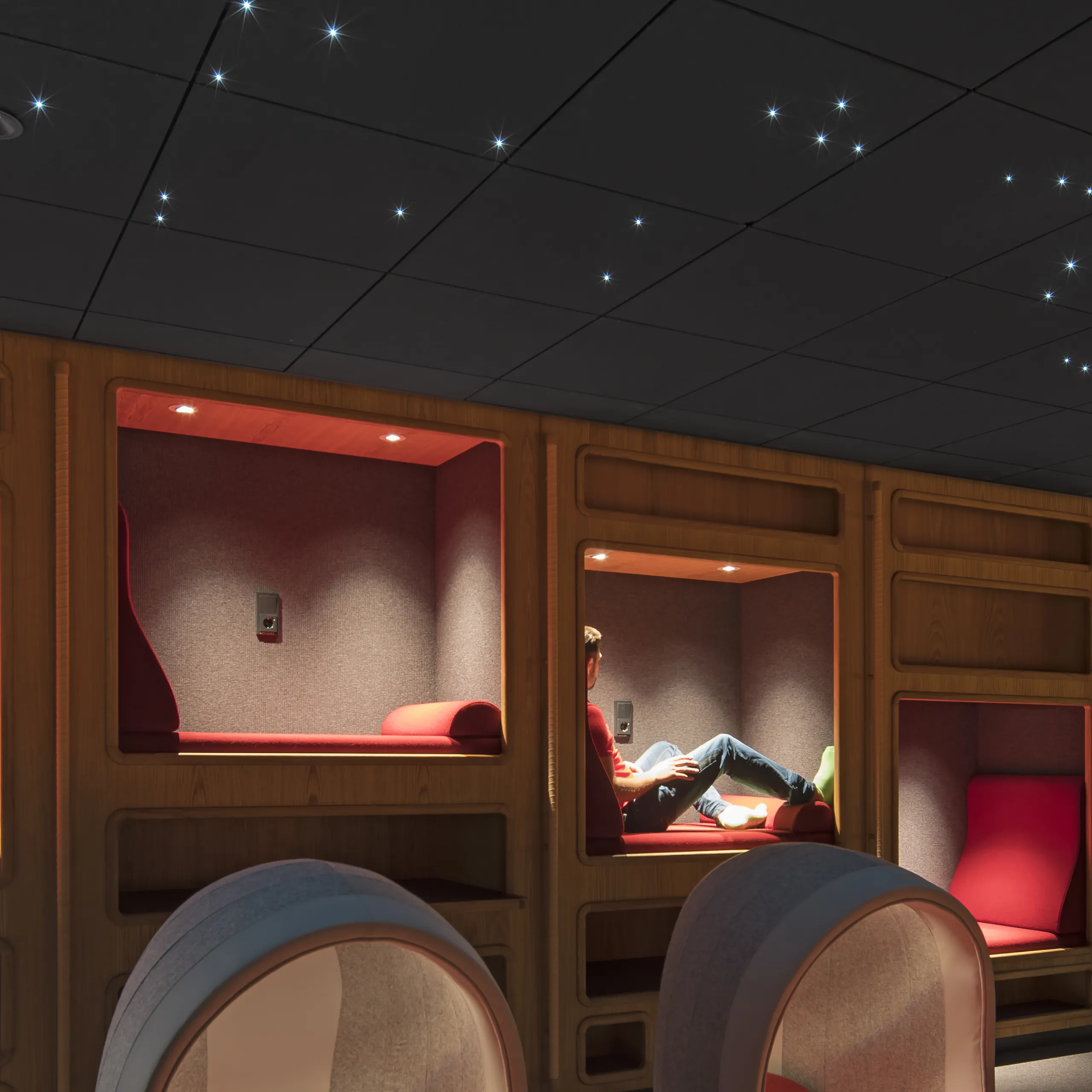 A warm reading alcove area lined with timber pods, illuminated by a dark acoustic ceiling sprinkled with star-like integrated LED points