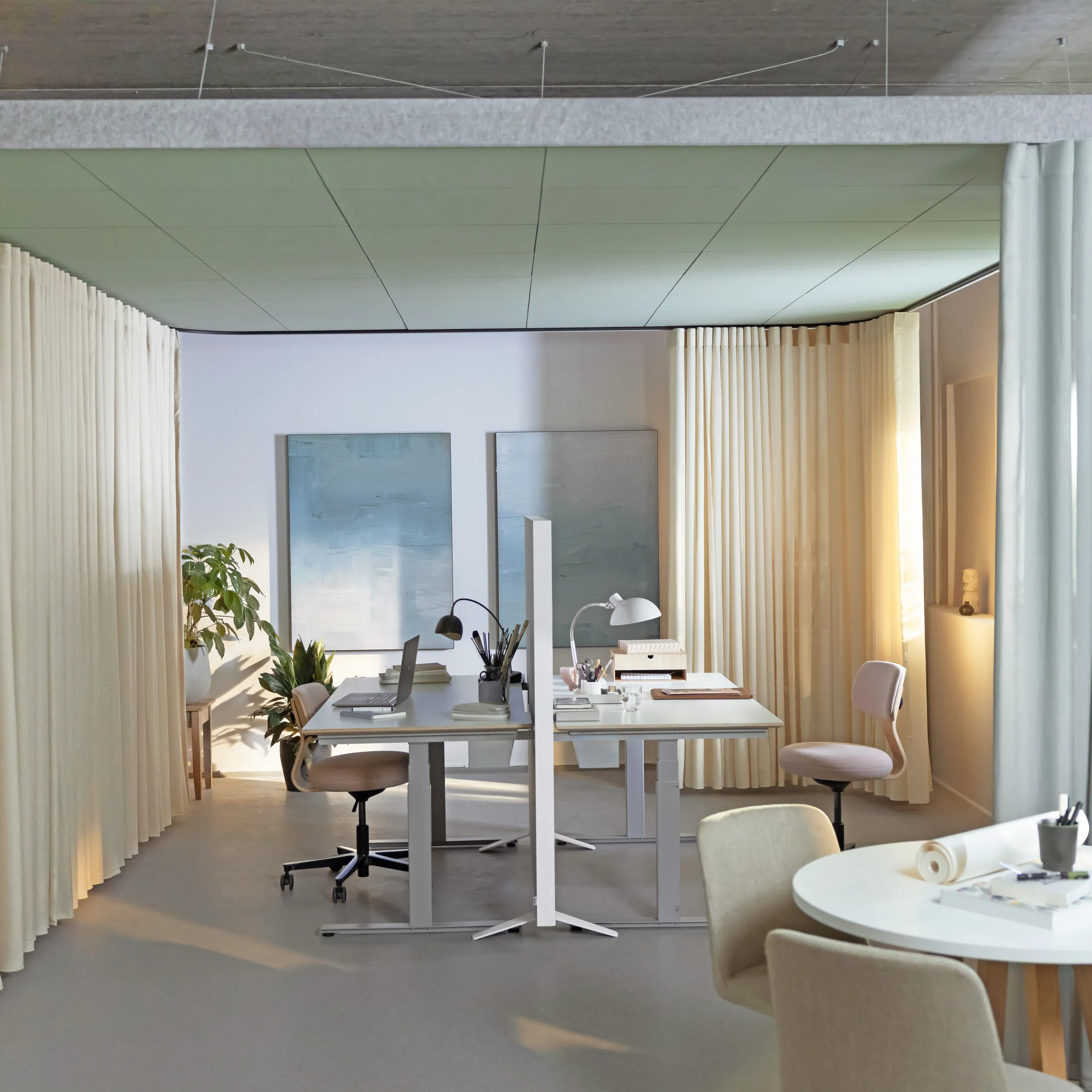 Workspace with suspended coloured acoustic ceiling panels forming a canopy above two desks, surrounded by floor-to-ceiling curtains