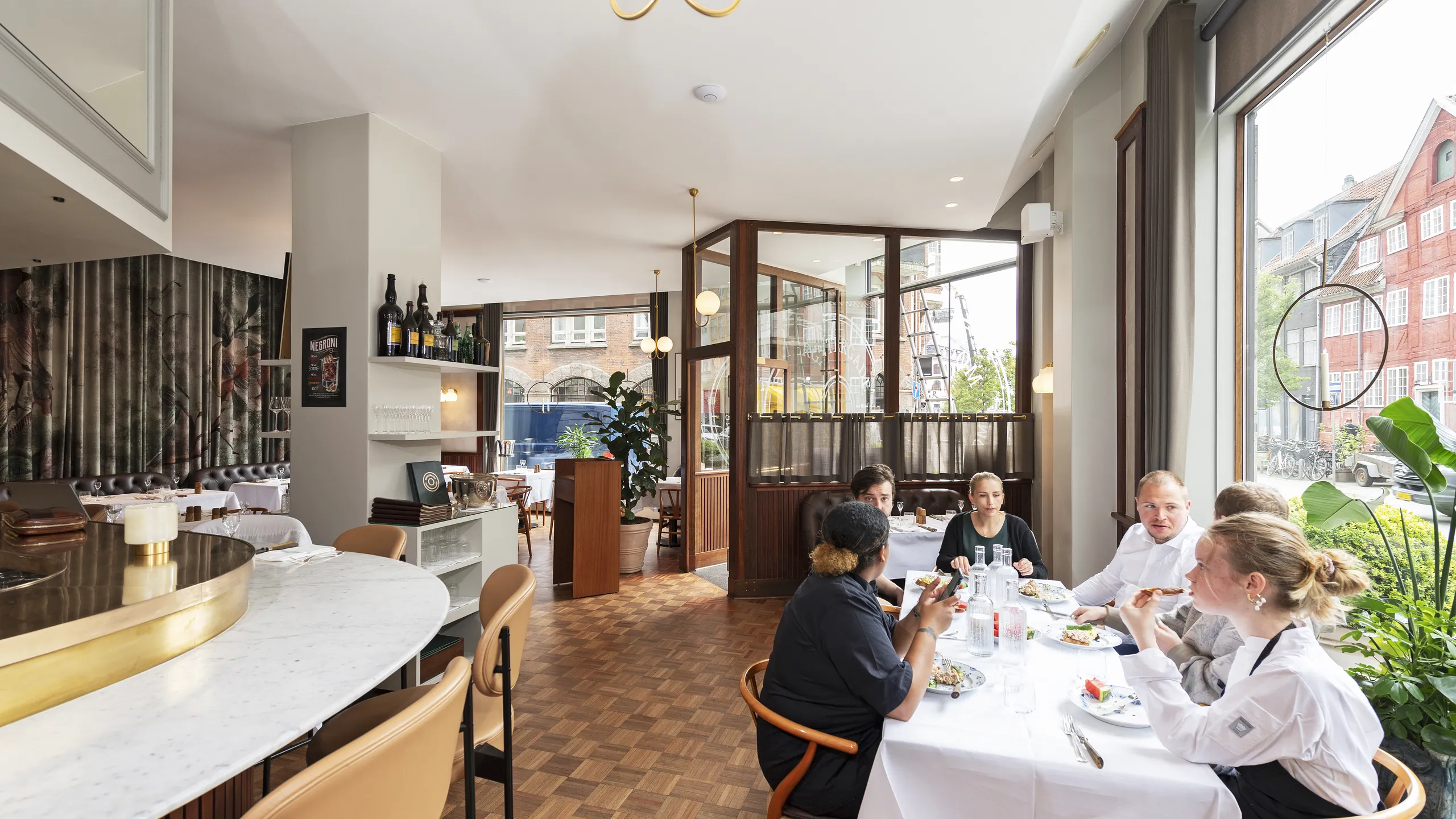 A group of people dining together without the Lombard Effect at a bright, modern restaurant with large windows and stylish decor.