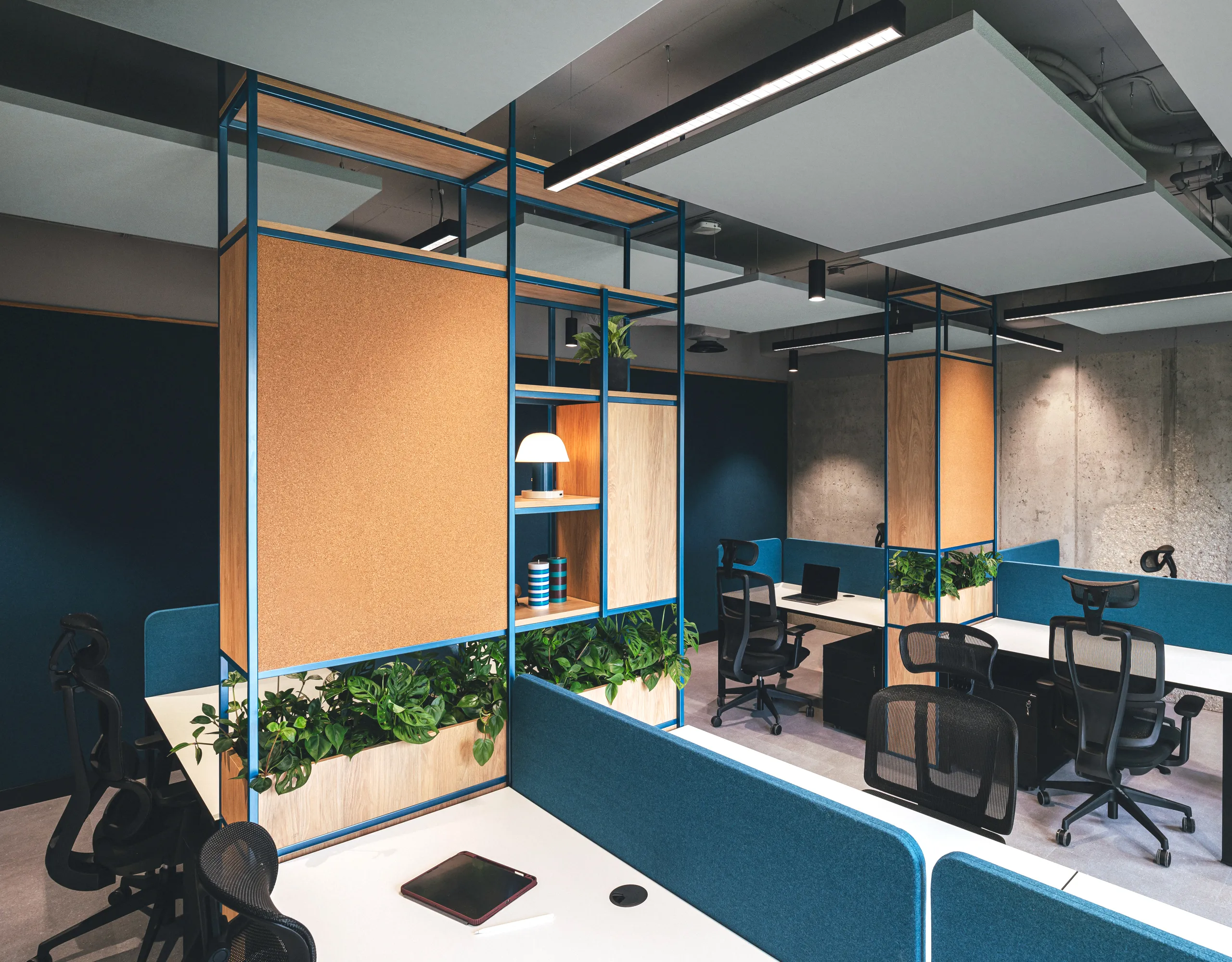 Contemporary office interior featuring floating acoustic ceiling islands, industrial exposed services, and workstation clusters framed by steel shelving