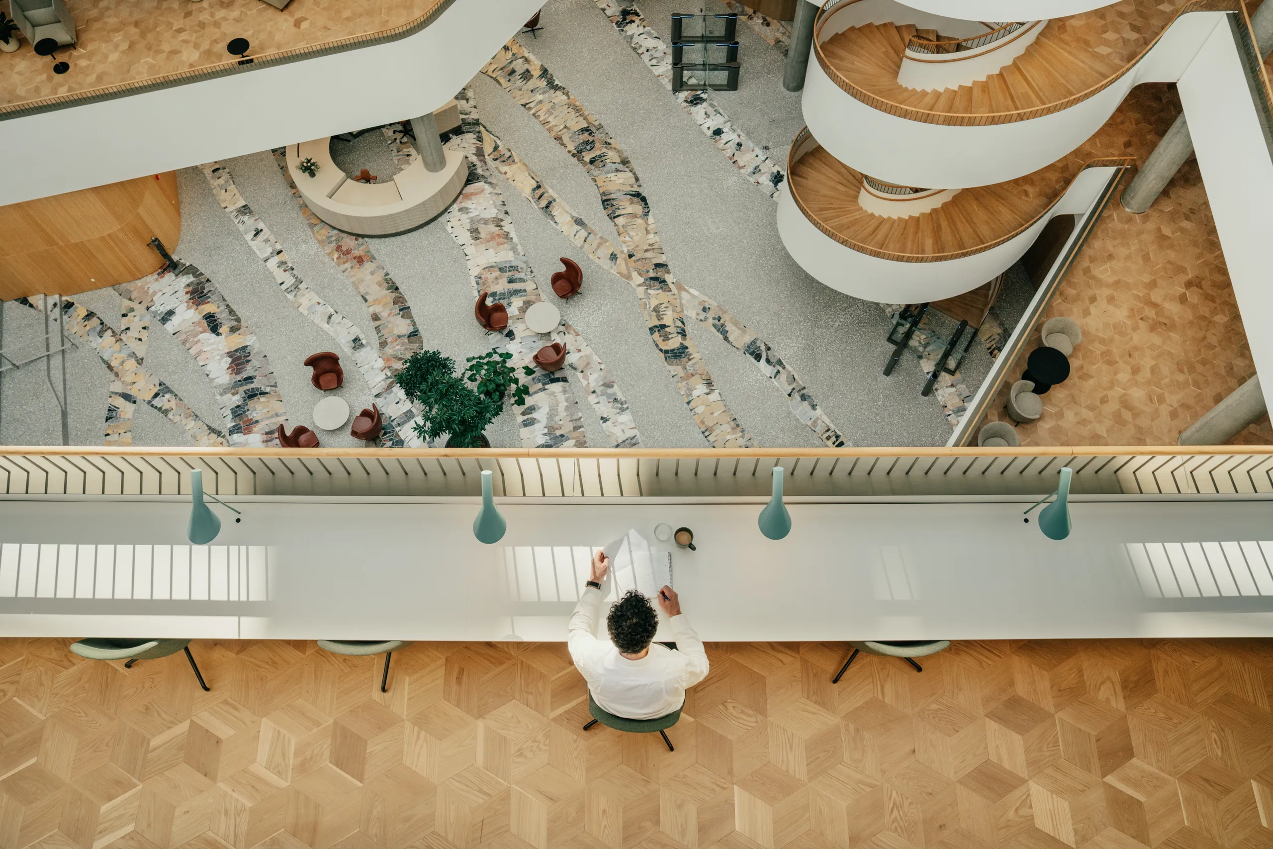 Contemporary atrium featuring seamless monolithic acoustic ceiling and wall finishes, flowing white balcony edges, green wall accents, and tall structural columns