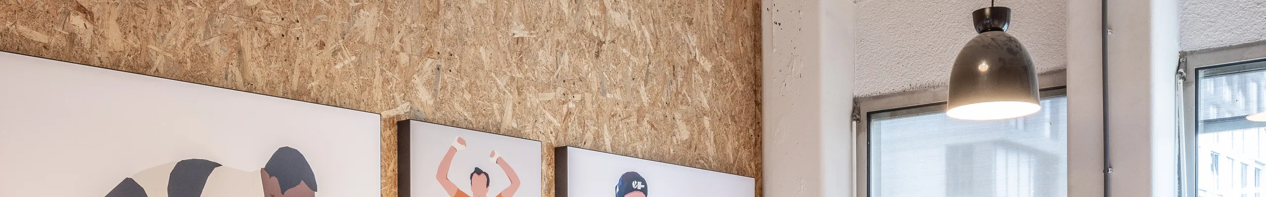 Meeting room with spray-applied acoustic ceiling absorber and acoustic wall panel, pendant lighting, and a long wooden table surrounded by black office chairs