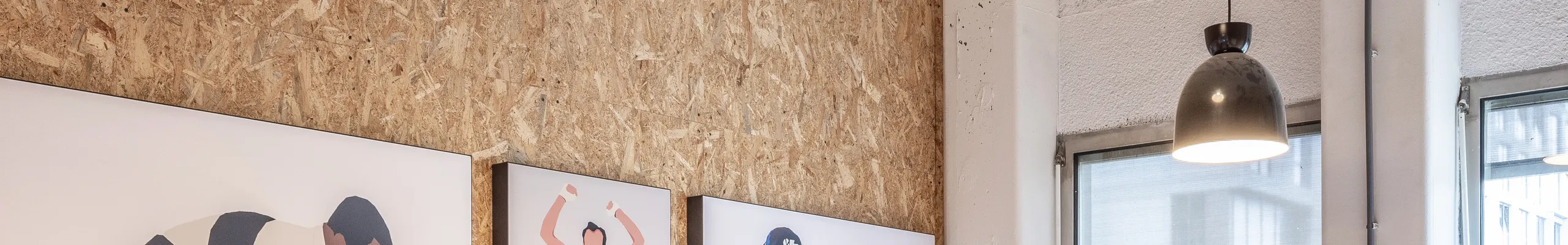 Meeting room with spray-applied acoustic ceiling absorber and acoustic wall panel, pendant lighting, and a long wooden table surrounded by black office chairs