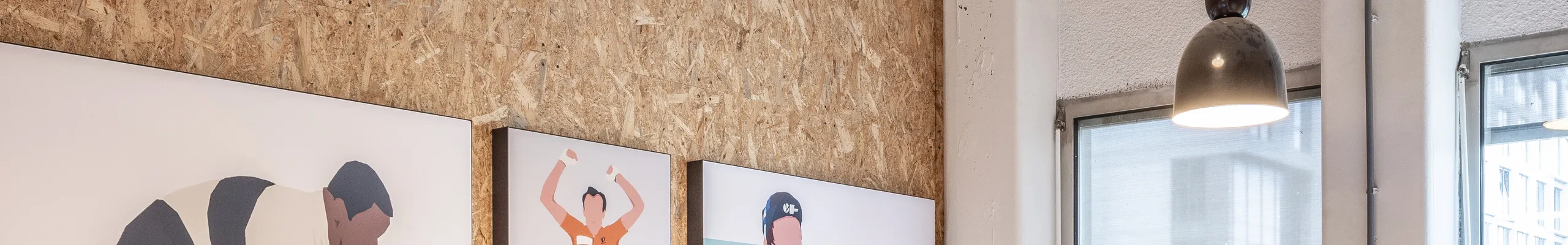 Meeting room with spray-applied acoustic ceiling absorber and acoustic wall panel, pendant lighting, and a long wooden table surrounded by black office chairs